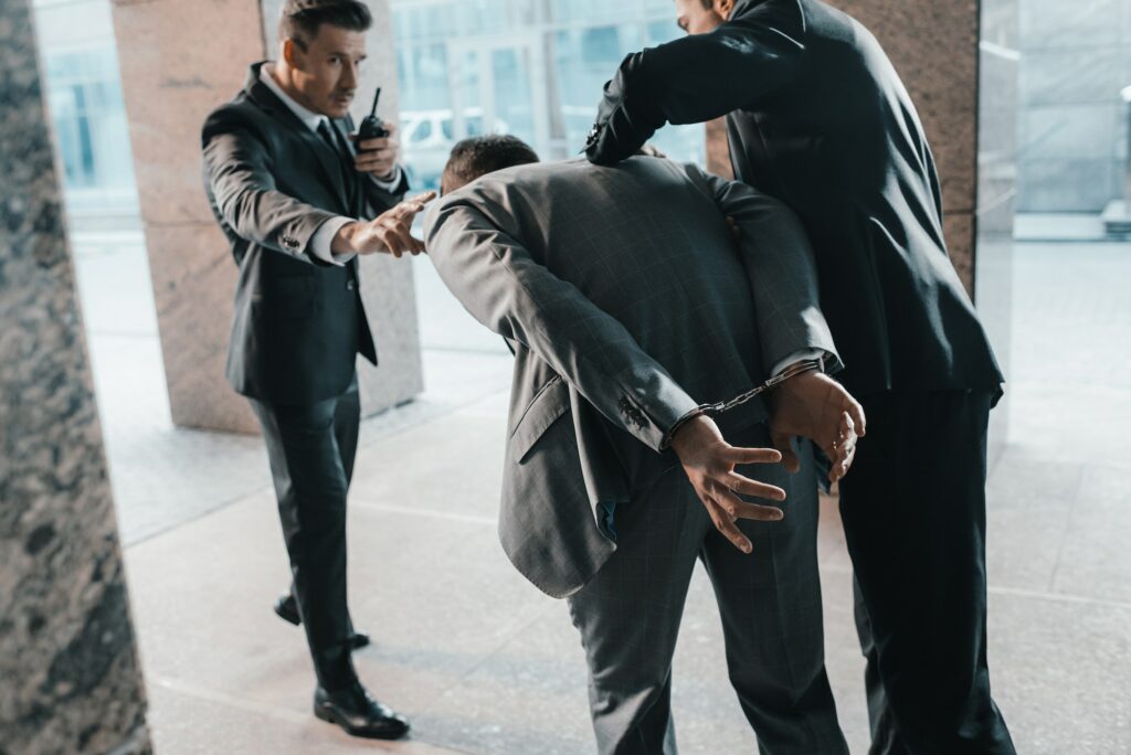 Cropped image of security guards arresting offender and talking by portable radio